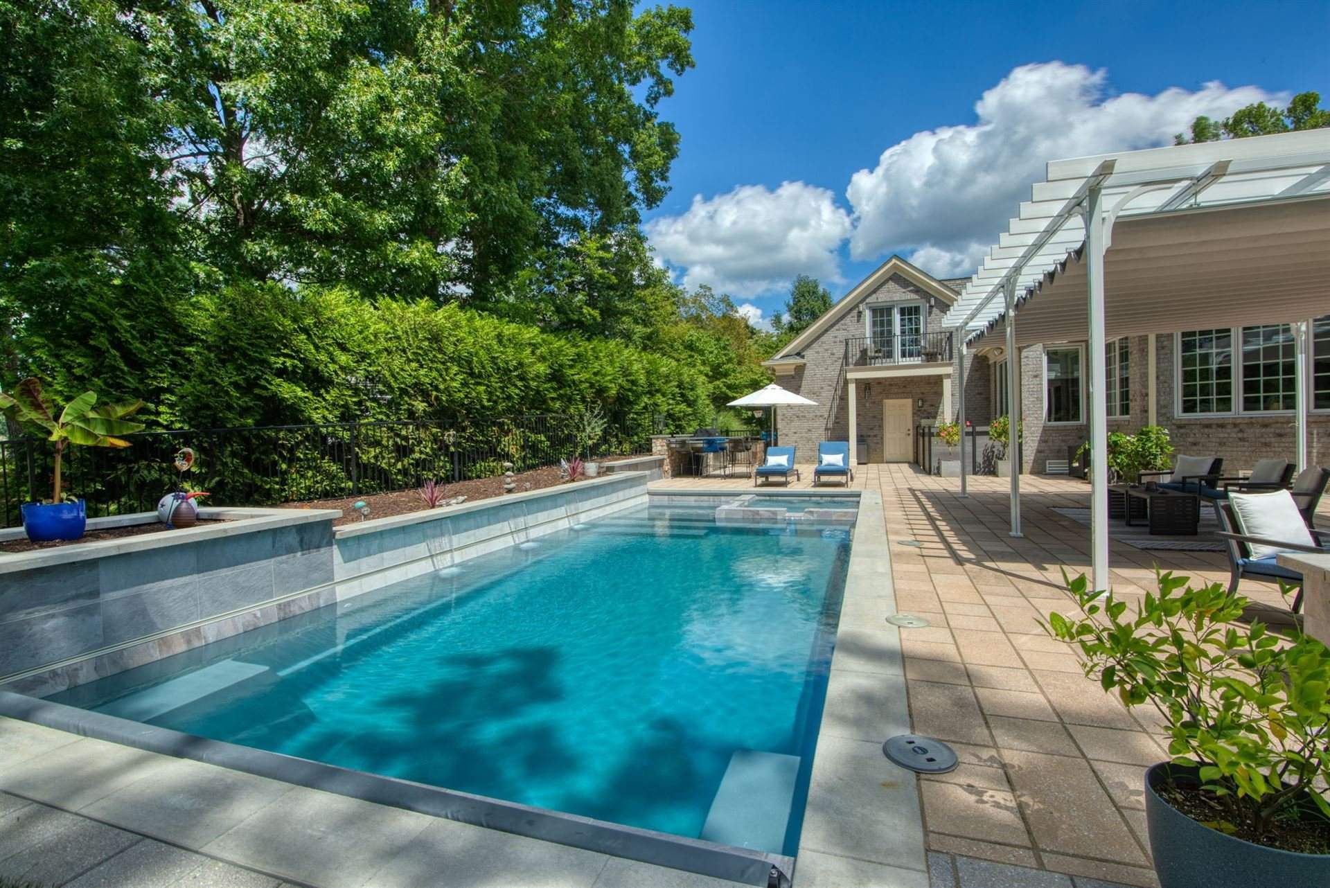 005. River Pools X36 in Granite Gray with cascade, concrete paver patio, and natural stone coping Image of an X36 fiberglass pool with tanning ledge and modern backyard patio design