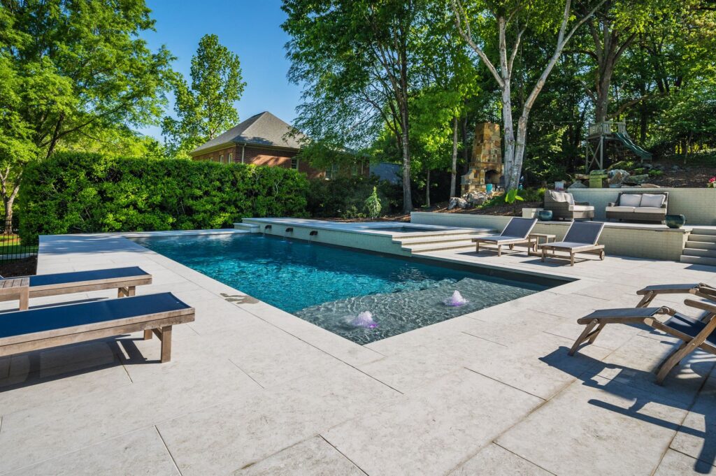 D40 Image of a luxury fiberglass pool with tanning ledge, lounge chairs, and landscaped backyard patio
