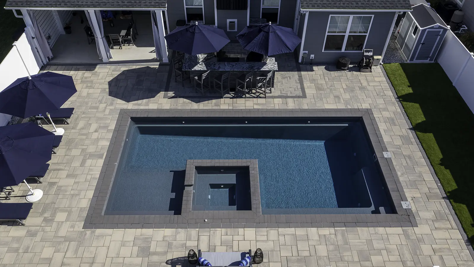 Image of an aerial view of The Exquisite fiberglass pool with built-in spa and large patio space