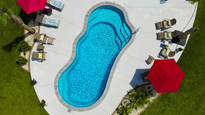 DJI_0811-800x450 Image of an overhead view of freeform fiberglass pools with red patio umbrellas and curved concrete decking