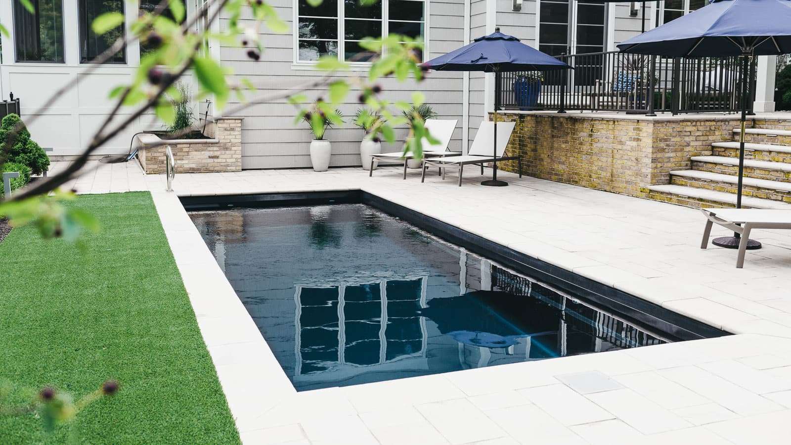 ImaginePools_Vision_26_VolcanicBlack_US_2018-1-1 Image of a modern rectangular fiberglass pool with dark finish and spacious patio area