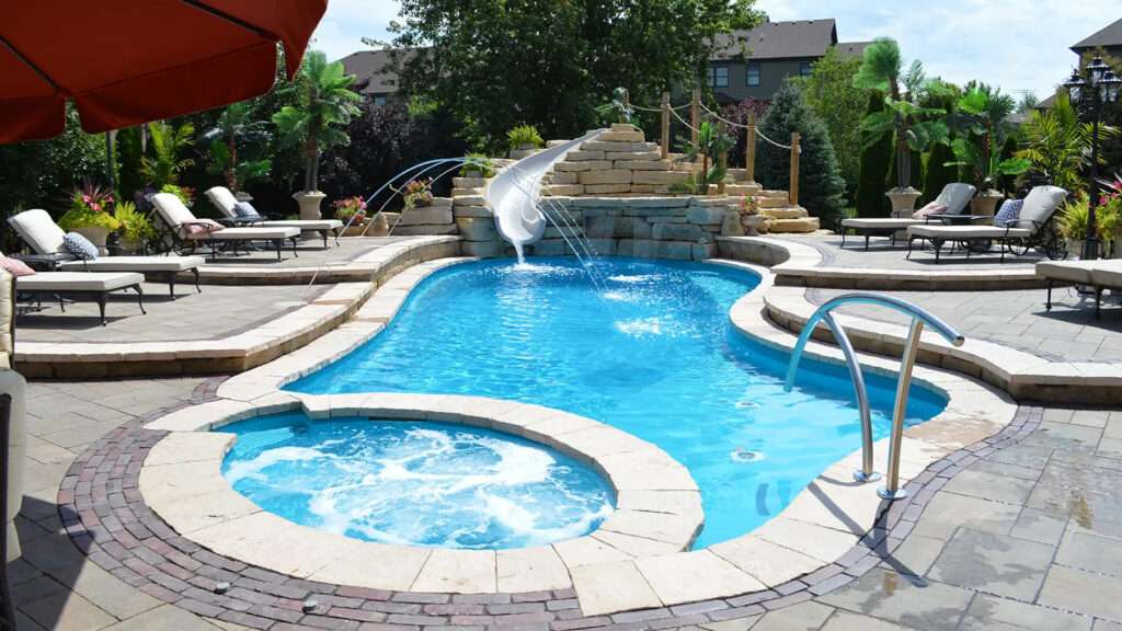 img-6 Image of a luxury fiberglass pool with attached spa, waterslide, and landscaped patio seating