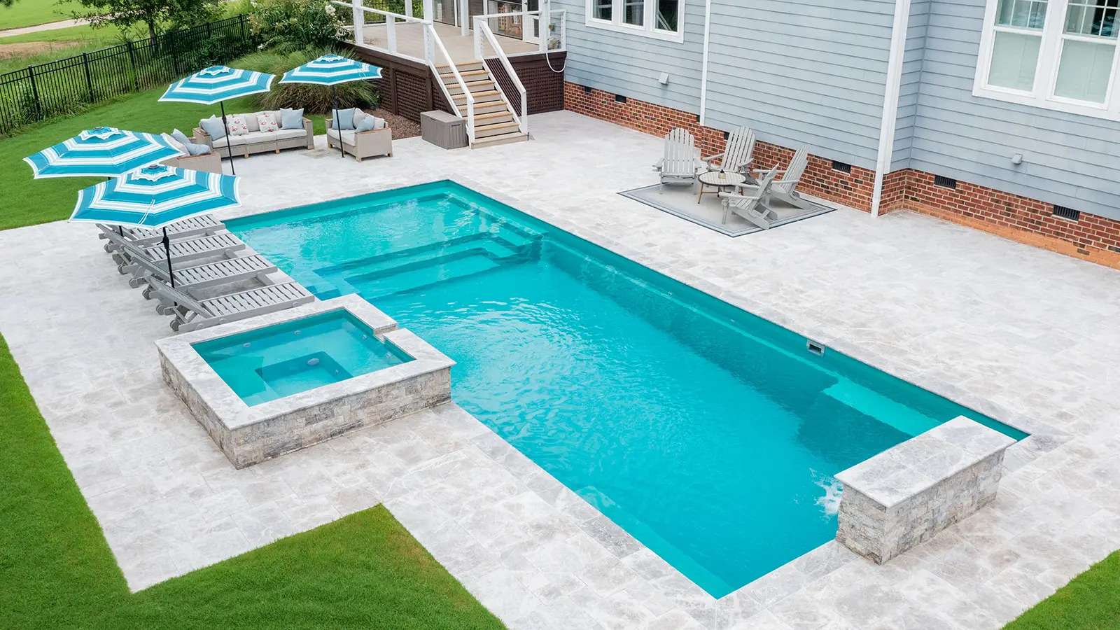Image of a rectangular fiberglass pool viewed from above with modern concrete patio and slide
