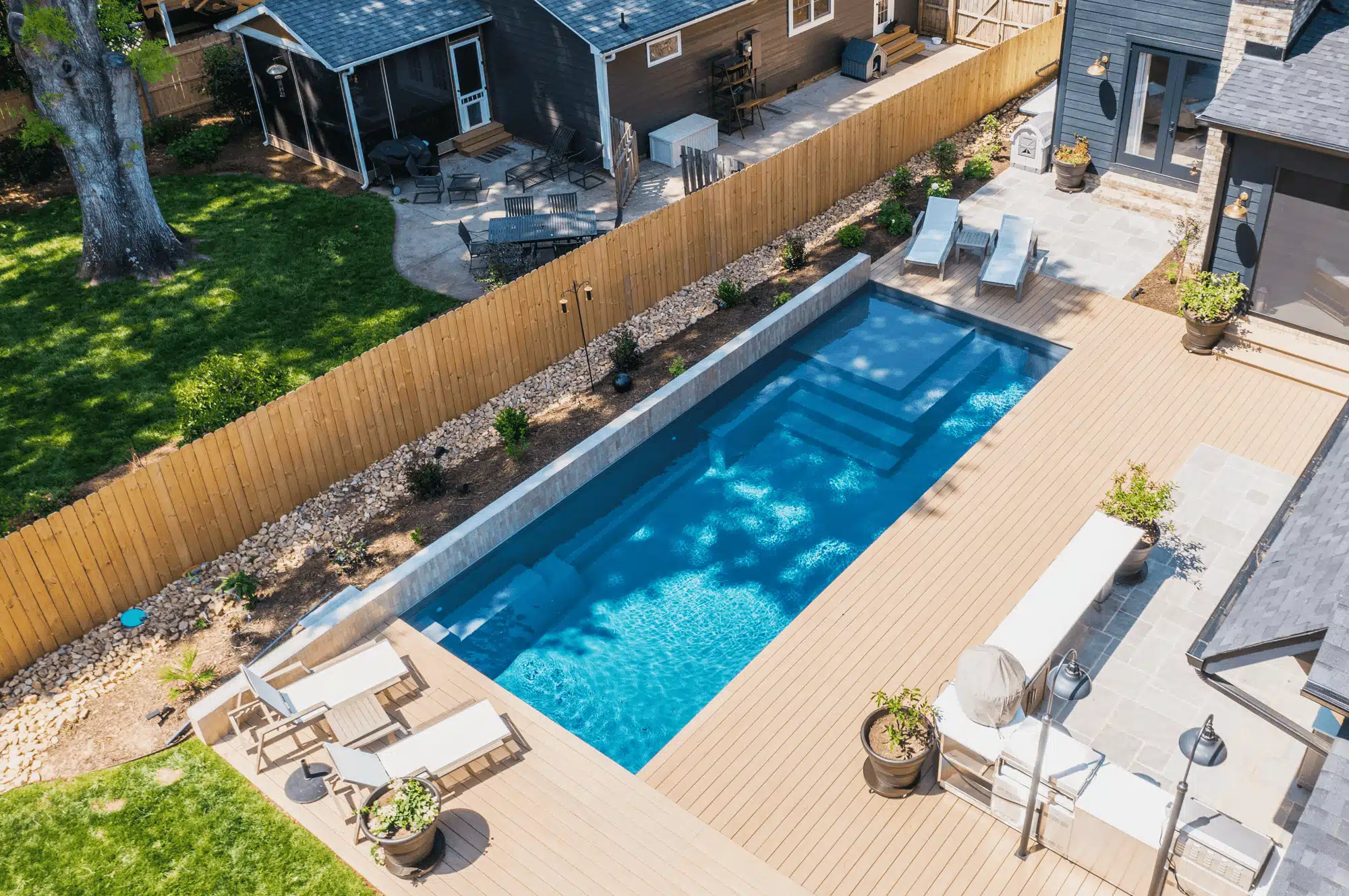 m35-fiberglass-pool-composite-wood-deck Image of a modern M35 fiberglass pool with composite wood decking and backyard lounge area