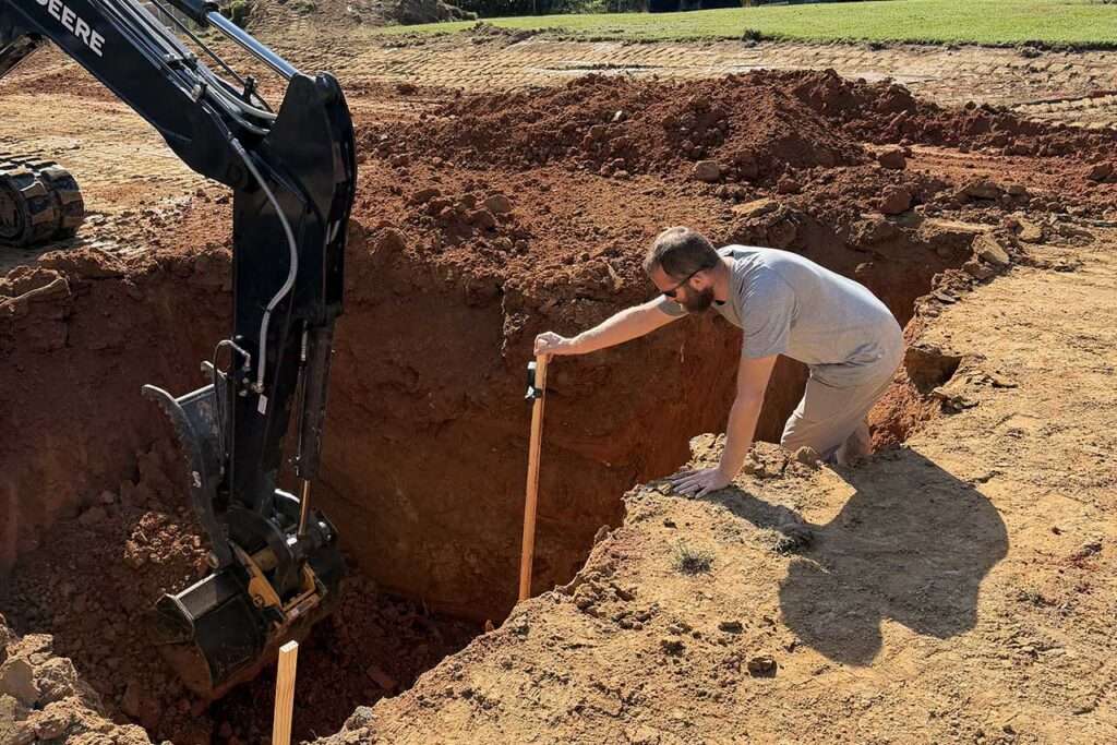 owner-on-site Image of contractor measuring excavation depth for fiberglass pools installation